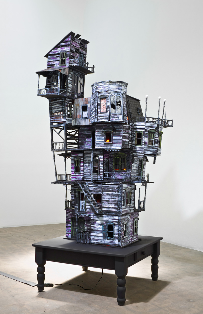 Richard Hawkins, <em>The Last House</em>, 2010. Altered dollhouse, lighting, and table, 89 x 36 x 36 in.