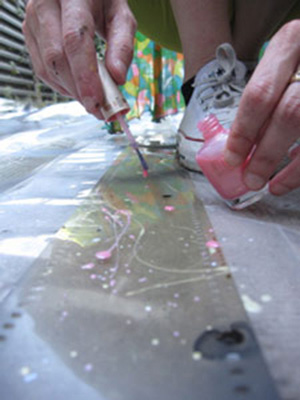 Jennifer West applying nail polish to film strips for <em>Lavender Mist Film/Pollock Film 1 (70mm film leader rubbed with Jimson Weed Trumpet flowers, spraypainted, dripped and splattered with nail polish, sprayed with lavender mist air freshener)</em>, 2009. 46 sec. Photo: Finn West.