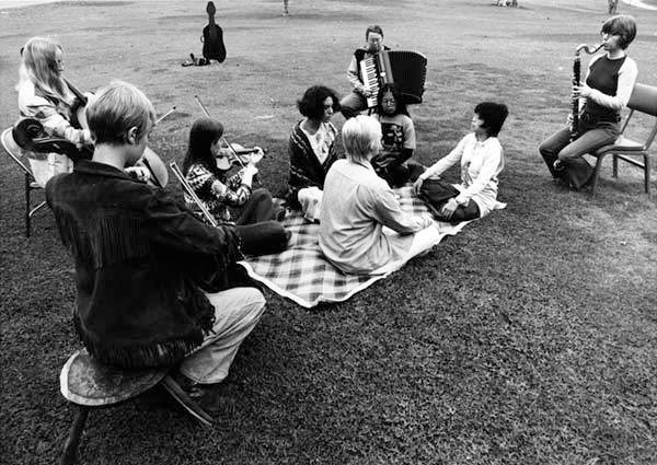 The ♀ Ensemble performing Teach Yourself to Fly from Sonic Meditations, 1970, Rancho Santa Fe, CA, (foreground to the left around: Lin Barron, cello, Lynn Lonidier, cello, Pauline Oliveros, accordion, Joan George, bass clarinet. Center seated foreground to the left around voices: Chris Voigt, Shirley Wong, Bonnie Barnett and Betty Wong). Pauline Oliveros Papers. MSS 102. Mandeville Special Collections Library, Univerisity of California, San Diego.